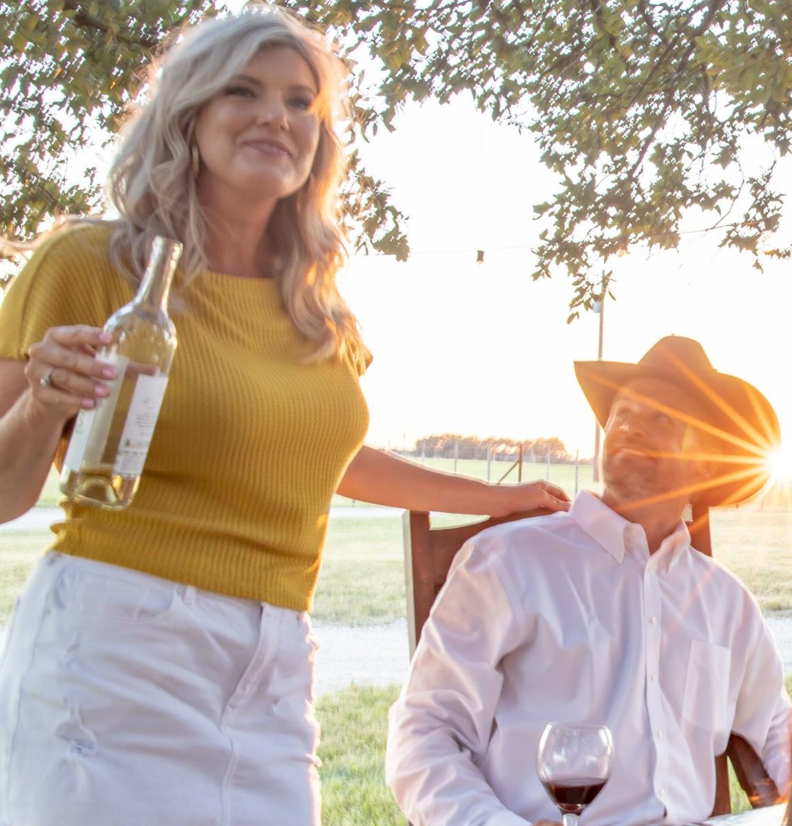 Jessica Richmond holding a bottle of wine beside Cade at an outdoor dinner on the ranch